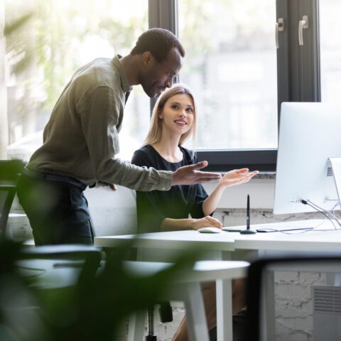 Office worker supporting a colleague using technology.