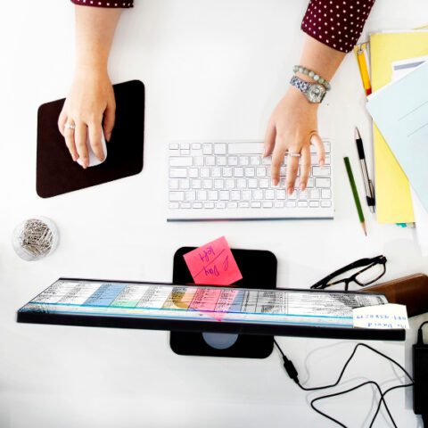 Professional multitasking with a laptop, phone, and notebook.