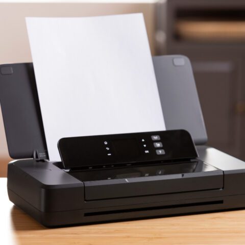 a desktop printer, revealing huge bills labelled "Hidden Business Print Costs," illustrating true costs. Maximise savings.