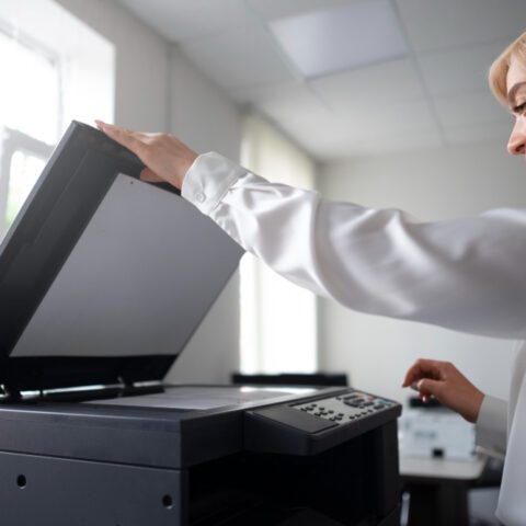 Professional woman operating an MFP with money visible, highlighting Multi-Function Printers Cost Savings to maximise office budget.